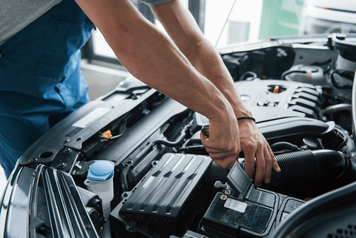 Automechanic checking the condition of a car battery.
